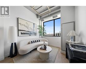 A well-lit, modern living room with a large window and a white sofa.