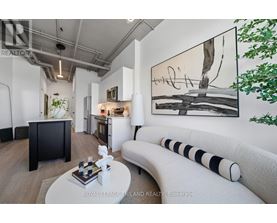 A modern living room with a large painting on the wall and a white sofa.