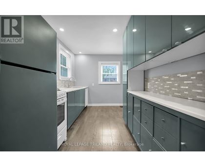 A modern kitchen with a black refrigerator and wooden floors.