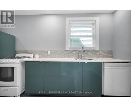 A kitchen with a white stove top oven, a white sink, and green cabinets.