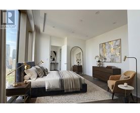 A bedroom with a large bed, a chair, and a painting on the wall.