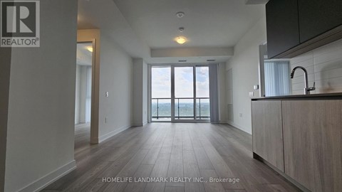 A spacious kitchen with a sink and a window overlooking the balcony.
