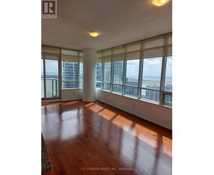 A large room with wooden floors and a view of the city through the windows.