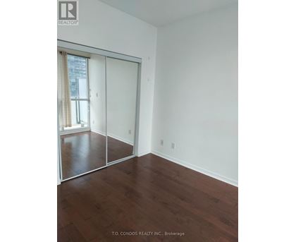 A room with a sliding glass door and wood flooring.