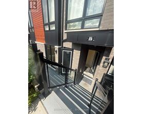 A building entrance with a black railing and steps leading to a door.
