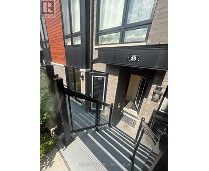 A building entrance with a black railing and steps leading to a door.