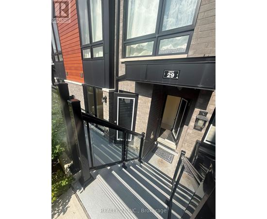 A building entrance with a black railing and steps leading to a door.