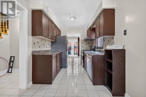 A kitchen with brown cabinets and a tiled floor.