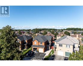 A real estate company logo is displayed on a sunny day in front of a row of houses.