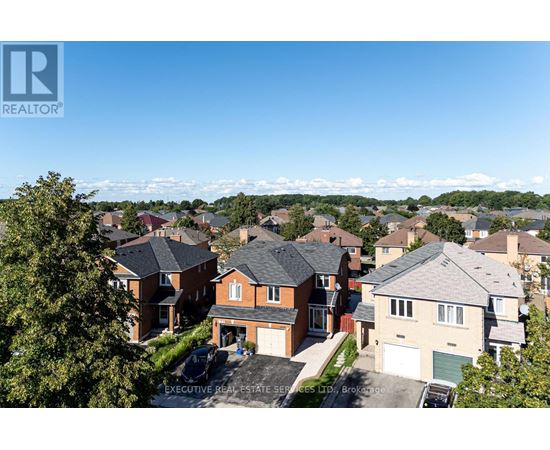 A real estate company logo is displayed on a sunny day in front of a row of houses.