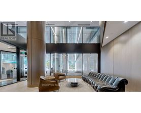 A modern waiting area with a long black leather couch and a wooden floor.