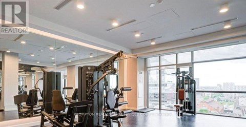 A gym with a row of treadmills and a row of stationary bikes.