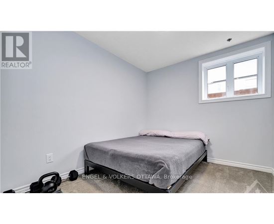 A bedroom with a bed, a window, and a kettlebell on the floor.