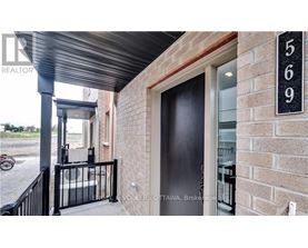 A black door with a glass window is on a brick wall.