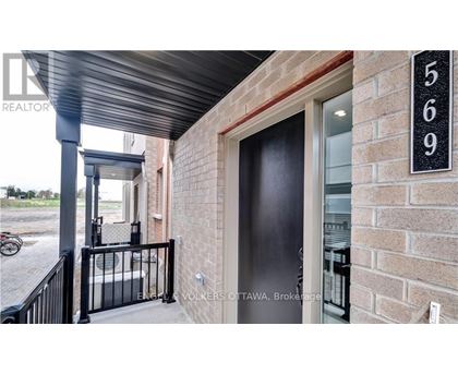 A black door with a glass window is on a brick wall.