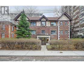 A brick apartment building with a tree in front of it.