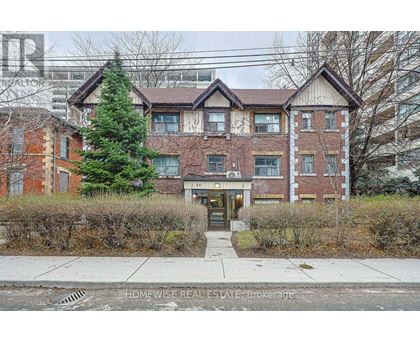 A brick apartment building with a tree in front of it.