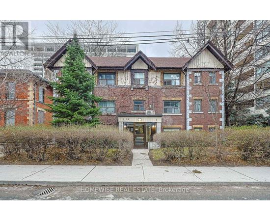A brick apartment building with a tree in front of it.