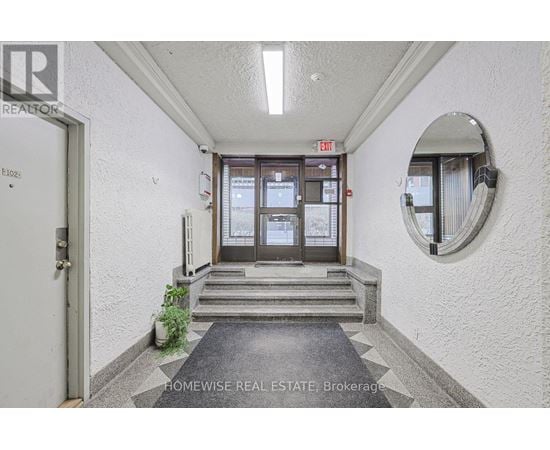 A hallway with a door and a mirror on the wall.