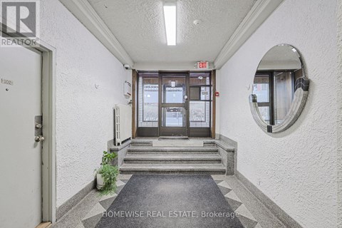 A hallway with a door and a mirror on the wall.