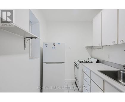 A white kitchen with a refrigerator and a sink.