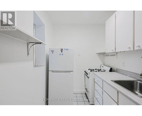 A white kitchen with a refrigerator and a sink.