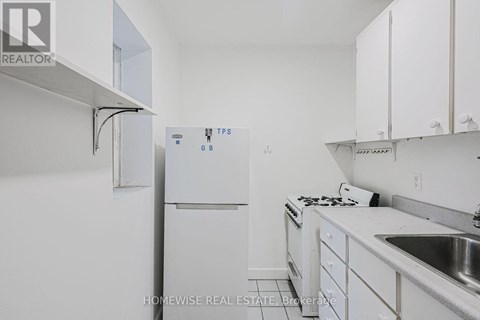 A white kitchen with a refrigerator and a sink.
