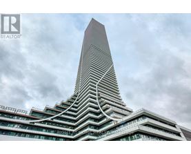 A tall building with a unique curved design stands against a cloudy sky.