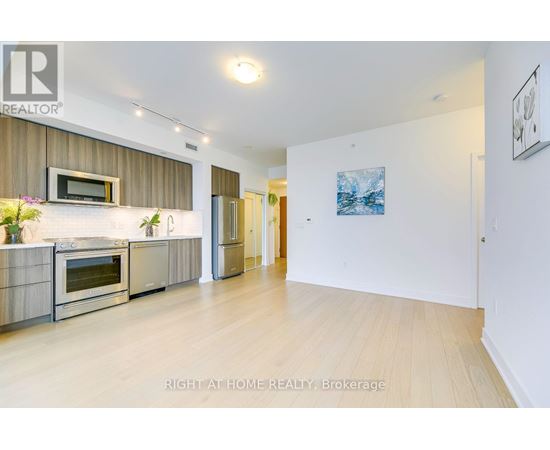 A modern kitchen with stainless steel appliances and wooden flooring.