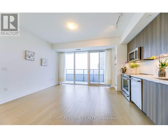 A spacious kitchen and living room with wooden floors and white walls.