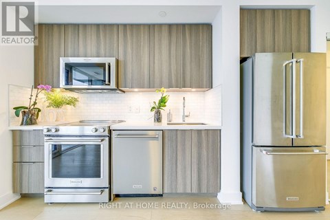 A modern kitchen with a stainless steel refrigerator and oven.