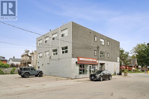 A grey building with a red sign that says "Vehicle Storage" in front of a black car.