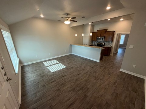 A room with a ceiling fan and wooden flooring.