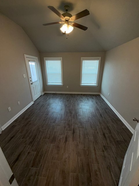 A room with a ceiling fan and wooden flooring.