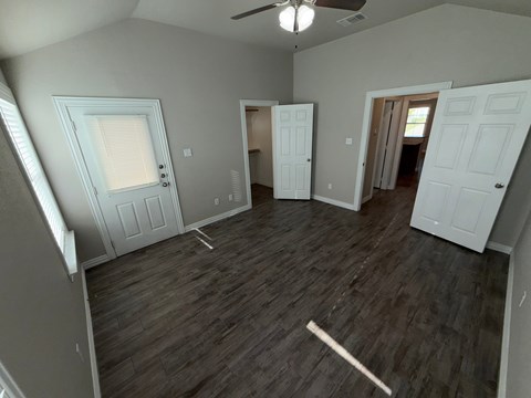 A room with a ceiling fan and wooden flooring.