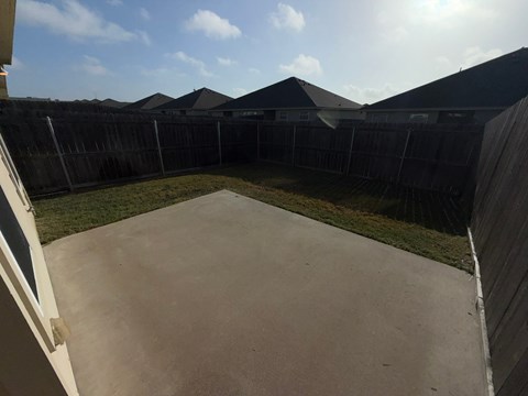 A concrete patio with a fence and houses in the background.