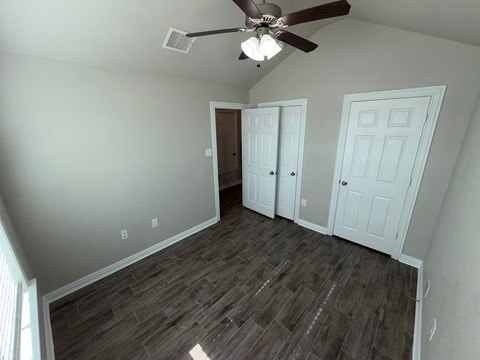 A room with a ceiling fan and two doors.