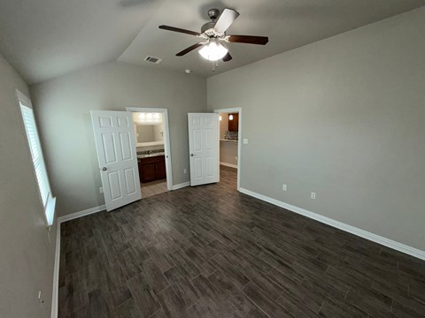 A room with a ceiling fan and two open doors.