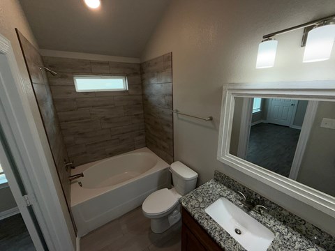 A bathroom with a white tub, toilet, and sink.