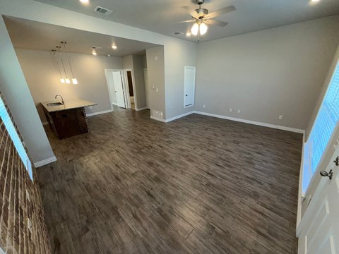 A spacious room with wood flooring and a ceiling fan.