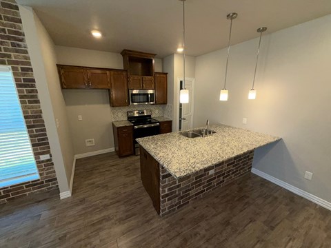A kitchen with a granite countertop and wooden cabinets.
