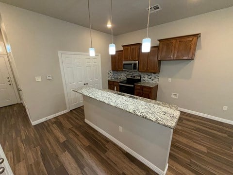 A kitchen with a granite countertop and wooden cabinets.