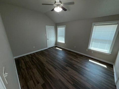 A room with a ceiling fan and two windows.