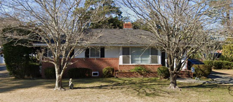 A house with a red brick chimney and a grey roof.