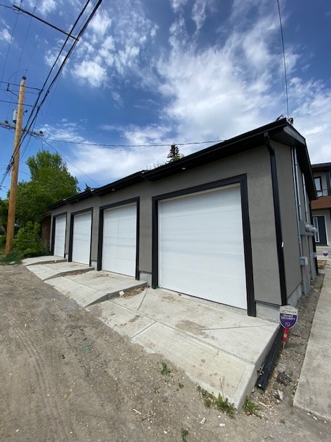 A grey building with a white garage door is on a street.