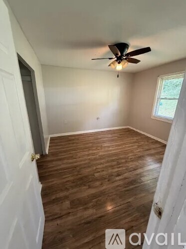 A room with a ceiling fan and wooden flooring.
