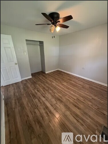 A room with wooden flooring and a ceiling fan.