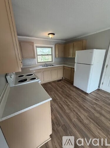 A kitchen with a white fridge and wooden floors.