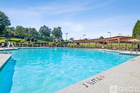 A large outdoor swimming pool with a wooden pergola and lounge chairs.