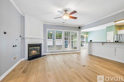 A spacious living room with a fireplace and a ceiling fan.
